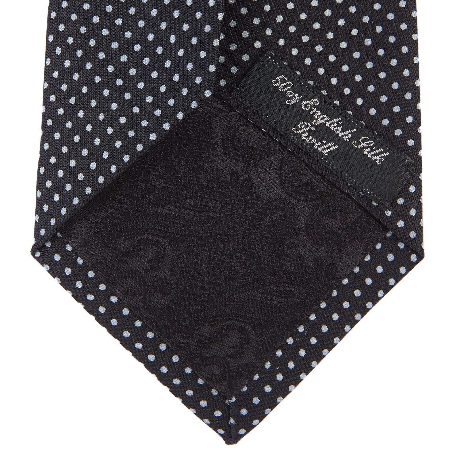 View 4 of product The Turnbull & Asser Black and White Spot Printed Silk Tie, shown neatly rolled on a plain white background, is an essential accessory to elevate any smart attire.