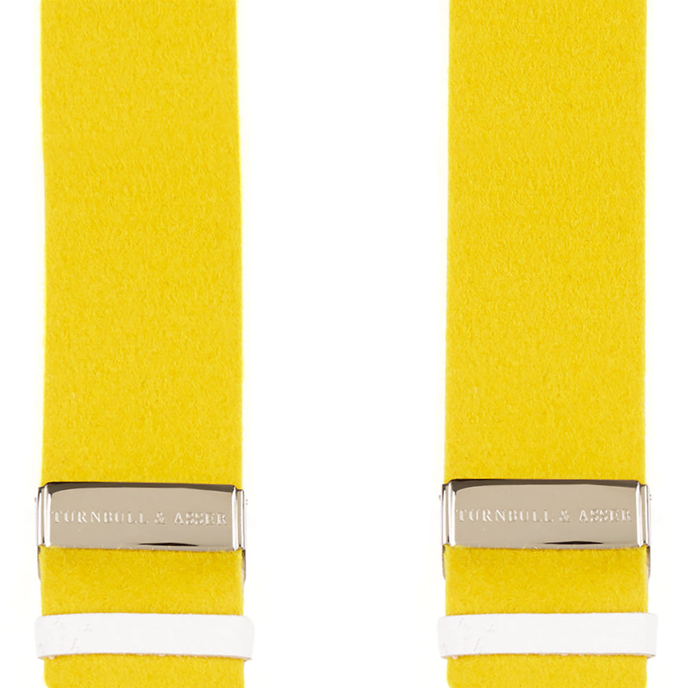 The Turnbull & Asser Golden Adjustable Felt Braces feature yellow elastic, silver metal clips, and white leather loops, evoking classic English style. Shown against a white backdrop.
