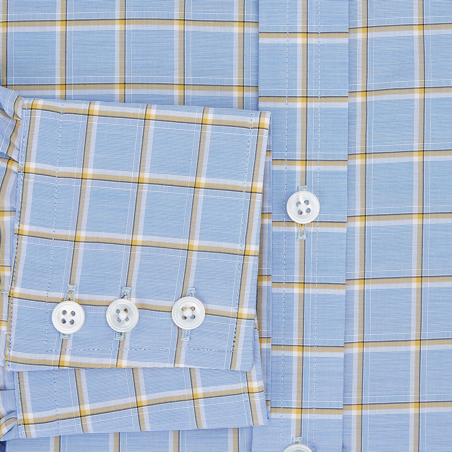 View 4 of product The Turnbull & Asser Blue and Yellow Windowpane Mayfair Shirt is crafted from fine Italian cotton, featuring a light blue base with yellow and white checks, shown on a plain white background.
