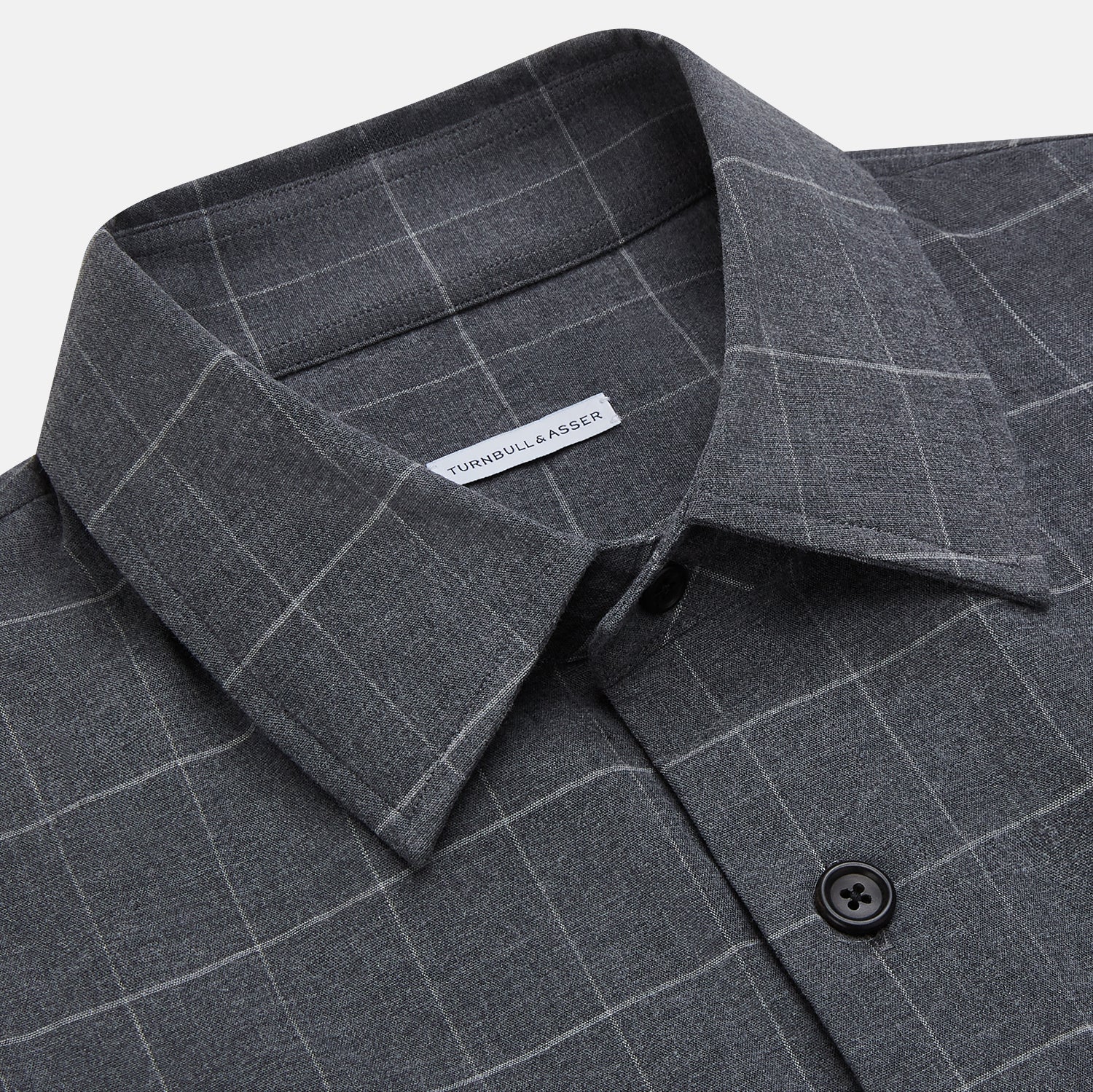 View 2 of product The Turnbull & Asser Charcoal Melange Check Hampstead overshirt, a long-sleeve button-up with a collar and two zippered side pockets, is laid flat on a light gray background.