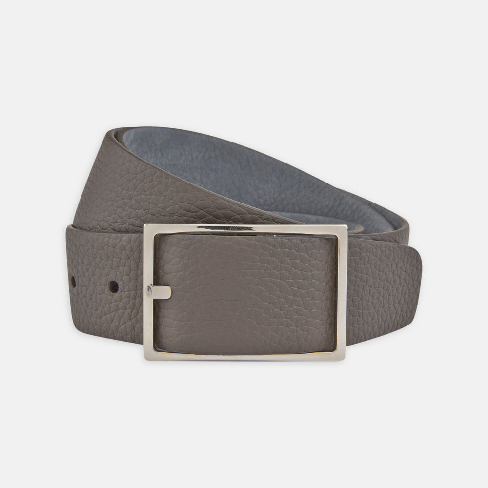 The Turnbull & Asser Nubuk Reversible Leather Belt is shown coiled on a plain white background, featuring gray textured leather and a rectangular silver buckle.