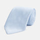 The HOUNDSTOOTH WHITE RIVER TIE by Turnbull & Asser features a light blue and white textured pattern, making it an essential accessory for elegant looks, shown beautifully rolled on a plain white background.