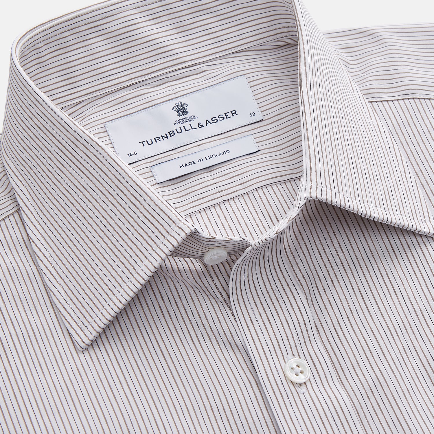 View 3 of product The Turnbull & Asser Sandstone Multi Stripe Cotton Regular Fit Mayfair Shirt, featuring long sleeves, button-up front, chest pocket, and classic collar with subtle white and light gray vertical pinstripes, is laid flat on a white background.