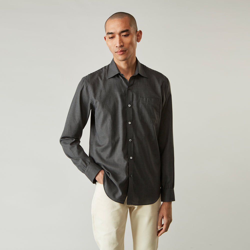 A man with short hair wears the Turnbull & Asser Black Check Weekend Fit Flannel Shirt with Derby Collar and 1-Button Cuffs, paired with light pants, against a plain background—ideal for a smart-casual weekend look.