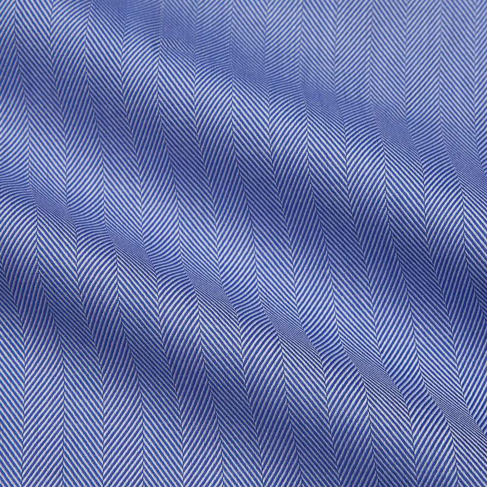 Turnbull & Asser's Blue Herringbone Tailored Fit Shirt with a Kent collar and white buttons is shown laid flat on a white background.