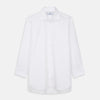 View 2 of product A woman with straight brown hair pulled back wears the Turnbull & Asser White Cotton Marlene Shirt, featuring classic menswear details, paired with high-waisted cream trousers against a neutral background.