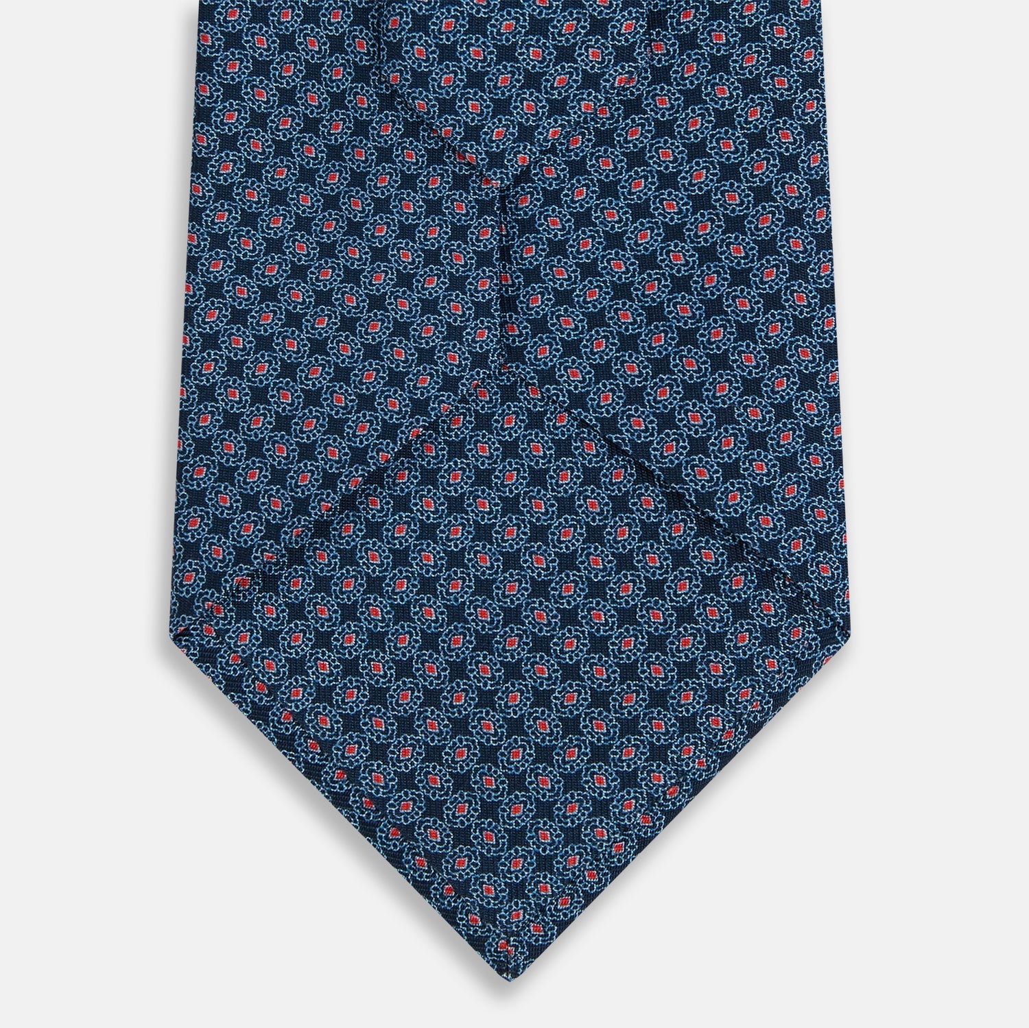 View 3 of product The Turnbull & Asser Navy and Red Rosette Silk Tie features a small repeating red and light blue geometric pattern on white, crafted from fine English silk.