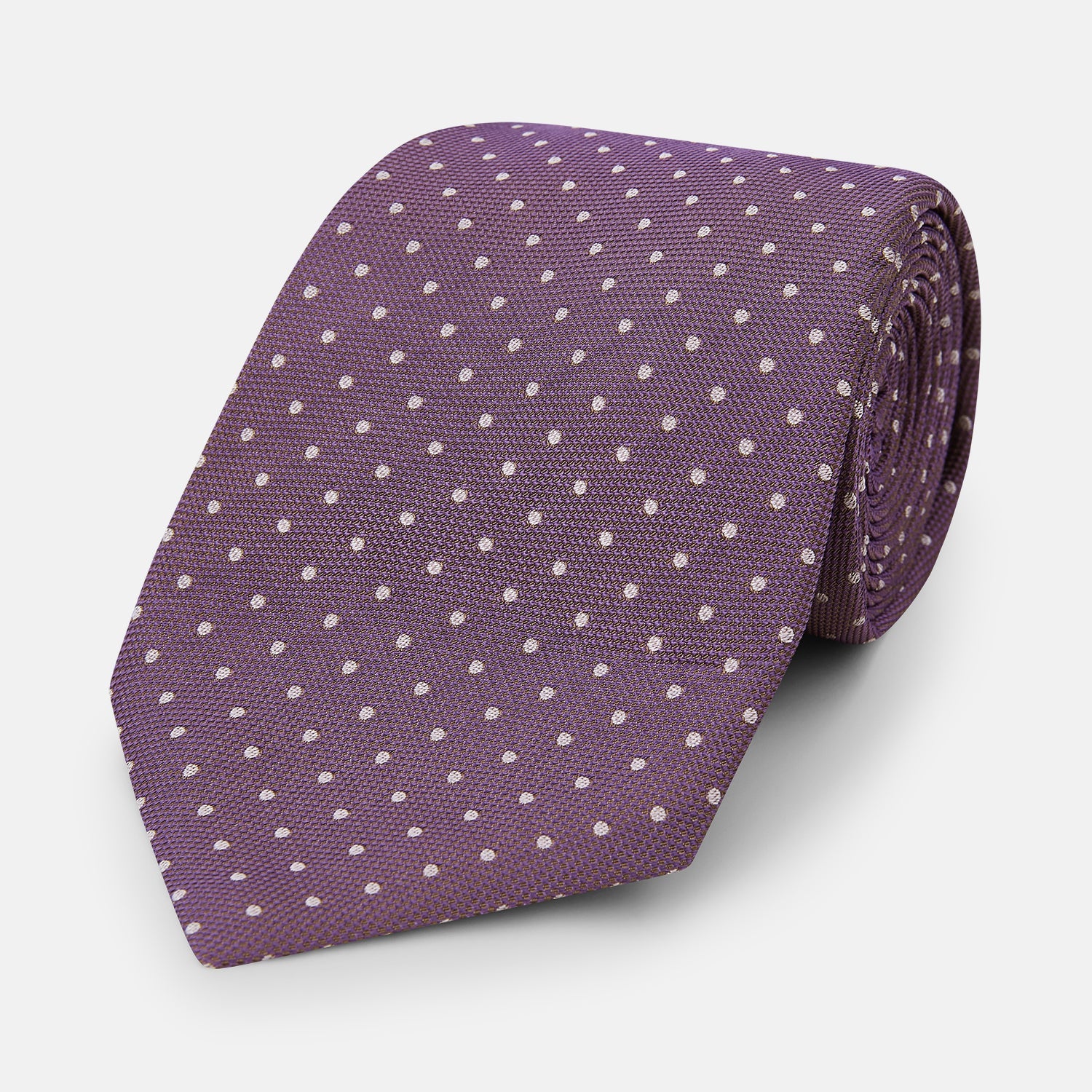 View 1 of product The Turnbull & Asser Lilac and Purple Micro Dot Silk Tie, featuring small white dots, is a stylish accessory for smart attire. Displayed rolled-up on a light background.