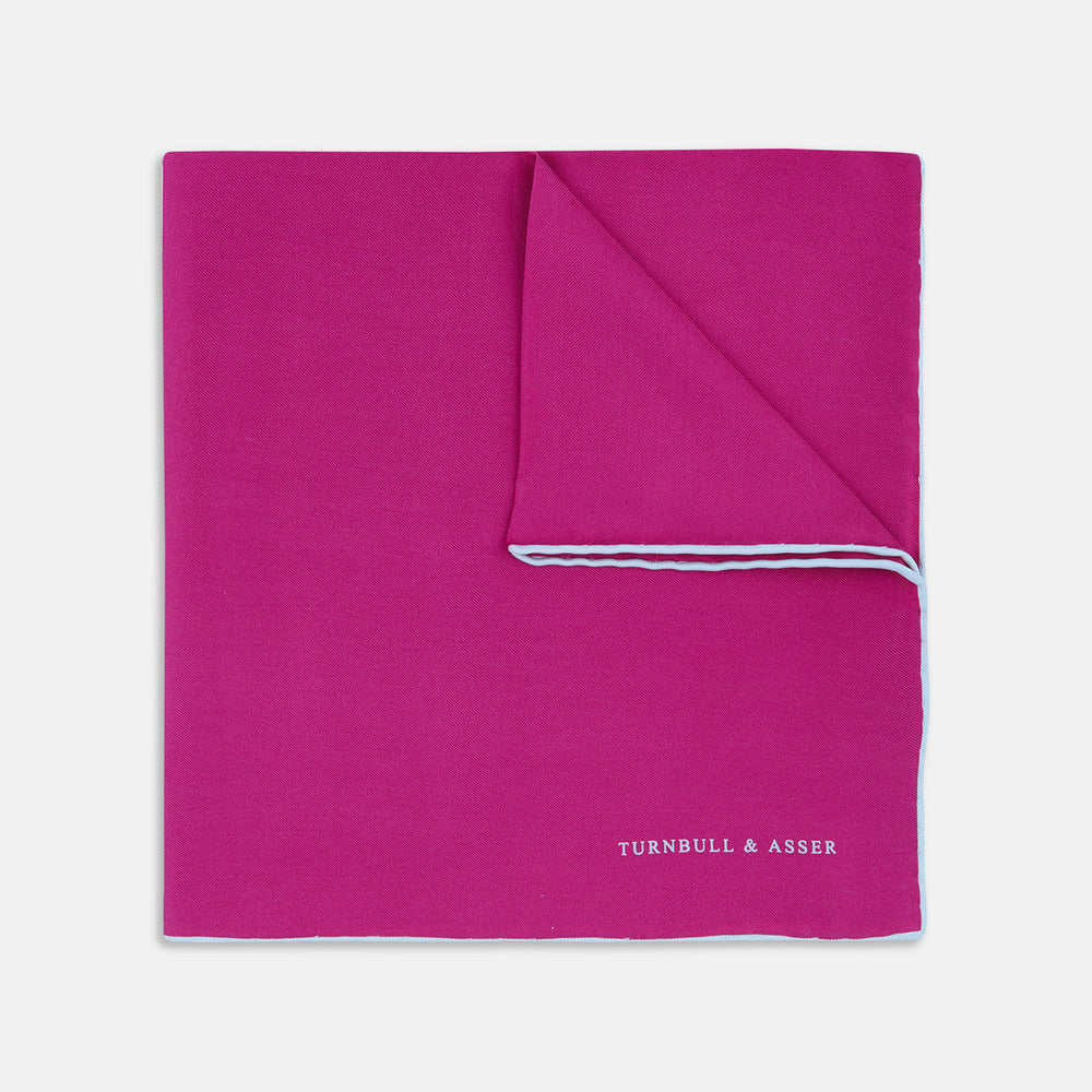 The Fuchsia and White Piped Silk Pocket Square by Turnbull & Asser features white edges and the brand’s name printed in white in the bottom right corner—a timeless men’s accessory.