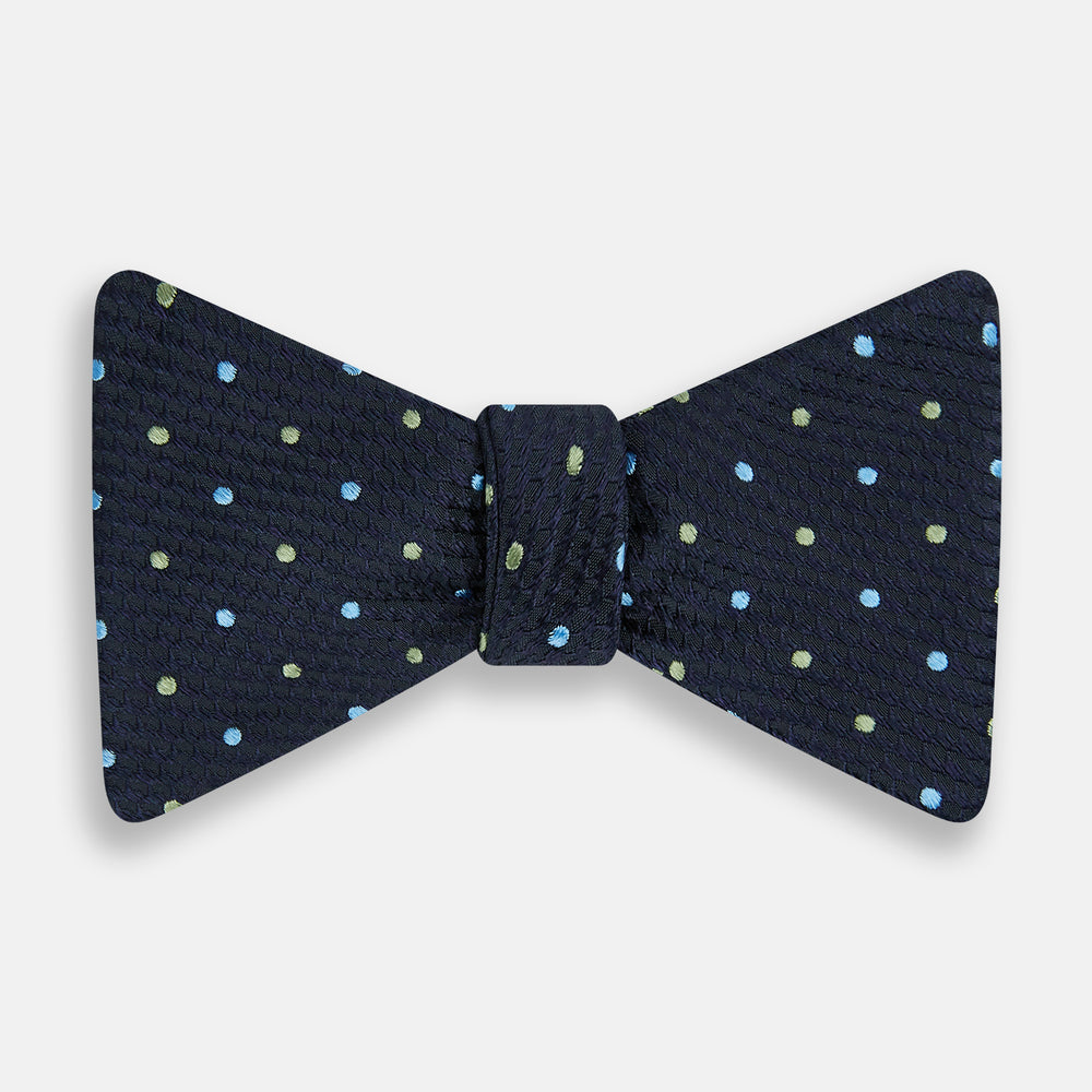 The Turnbull & Asser Lime Green and Sky Blue Spot Silk Bow Tie features a textured navy background with light blue and lime green polka dots, shown on a white background—a timeless men's accessory.