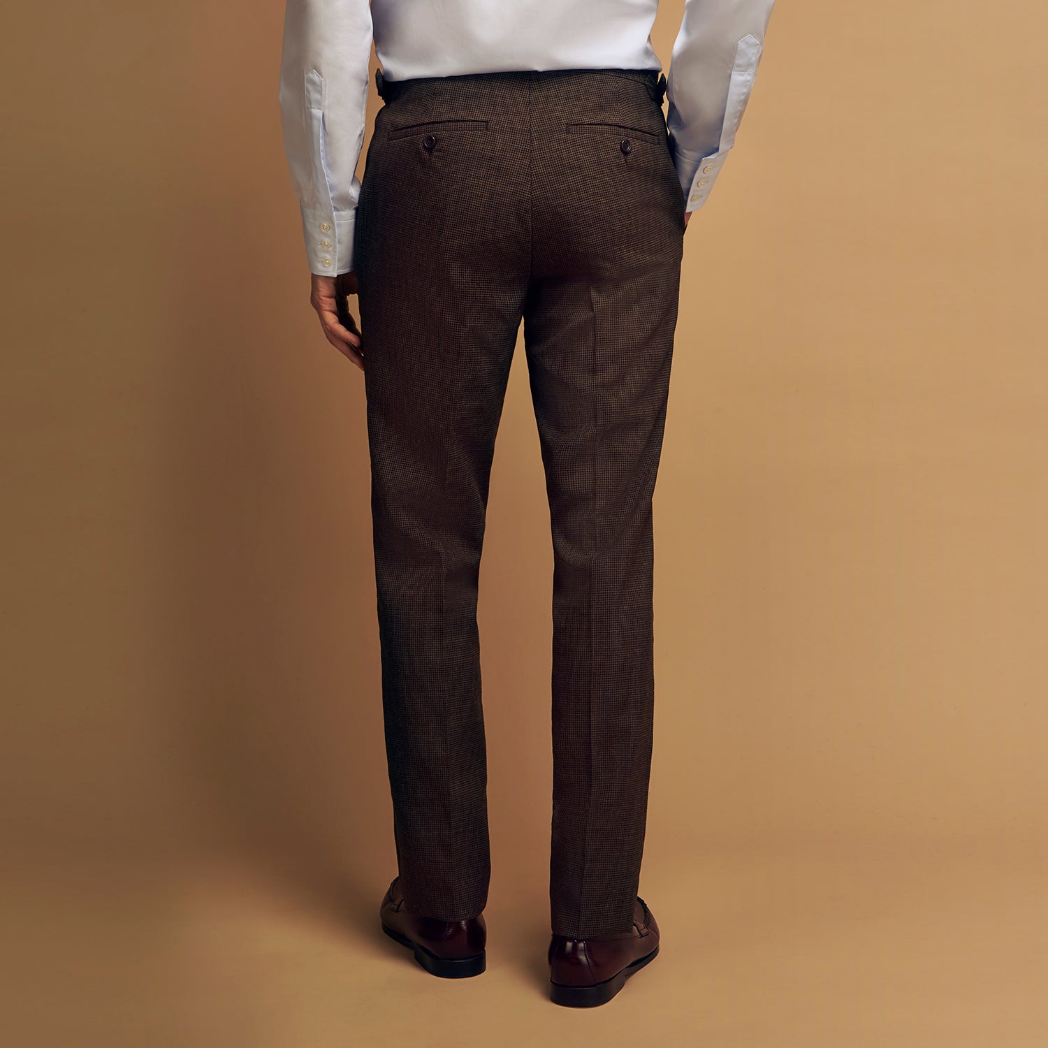 View 6 of product The Brown Puppytooth Wool Jonathan Trousers by Turnbull & Asser are straight-leg tailored trousers with belt loops, side pockets, and a front crease, shown on a white background.