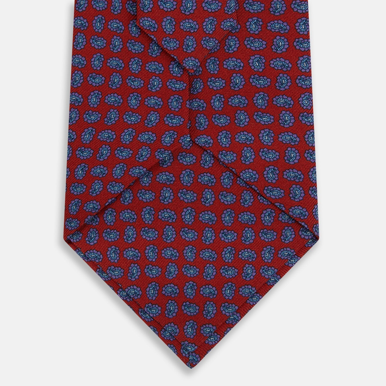 View 3 of product The Turnbull & Asser Red and Purple Miniature Paisley Silk Tie is neatly rolled with the pointed end facing forward.