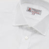View 5 of product A neatly folded Turnbull & Asser Two-Fold 200 White Cotton Shirt with a Regent collar and 3-button cuffs, crafted from breathable fabric, is displayed on a light grey background with the label visible inside the collar.