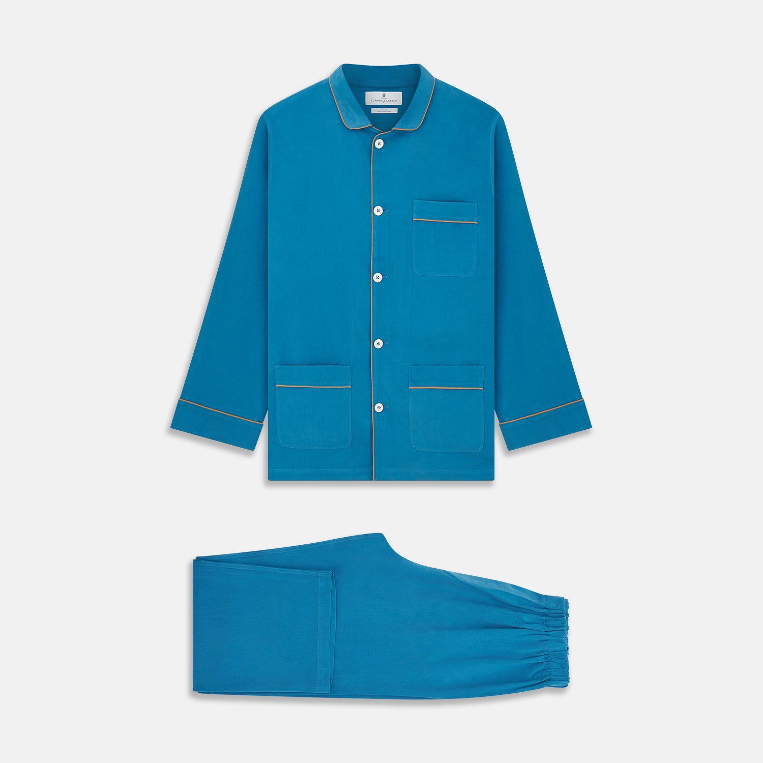 View 1 of product The Turnbull & Asser Blue Silk Hyde Pyjama Set features a modern fit with a long-sleeve button-up top, three pockets, white trim, and elastic-waist pants, all shown on a white background.