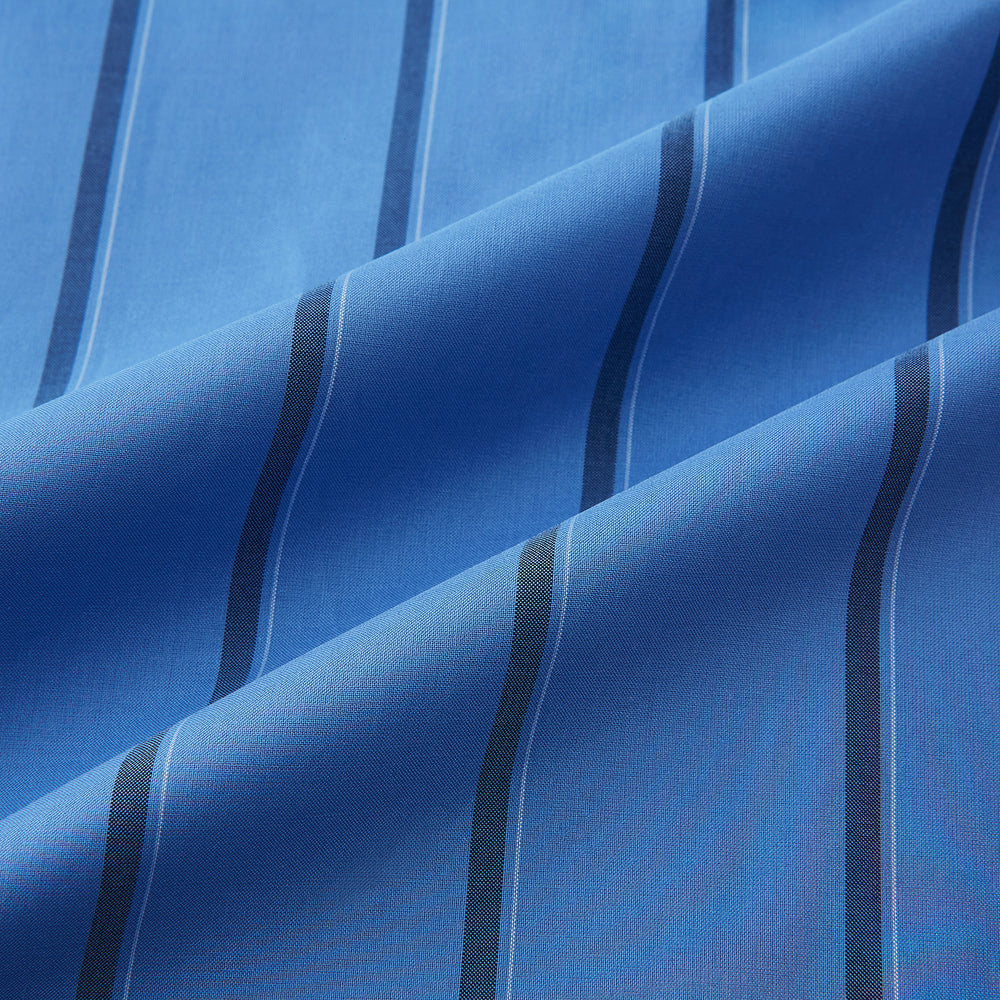 The Turnbull & Asser Colony Blue Track Stripe Shirt features vertical dark blue stripes, a Mayfair fit, and contrast white T&A collar and cuffs, reflecting British craftsmanship against a plain light background.