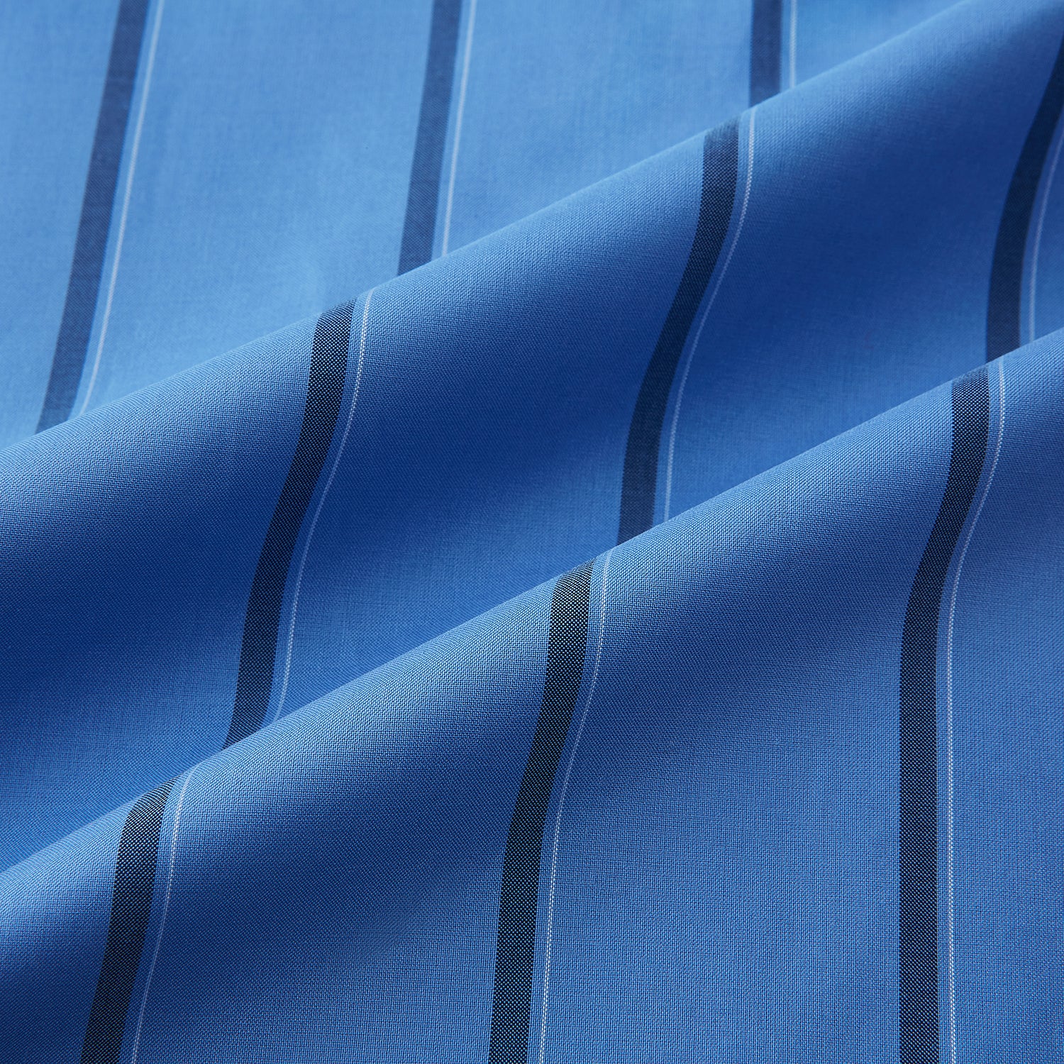 View 6 of product The Turnbull & Asser Colony Blue Track Stripe Shirt features vertical dark blue stripes, a Mayfair fit, and contrast white T&A collar and cuffs, reflecting British craftsmanship against a plain light background.