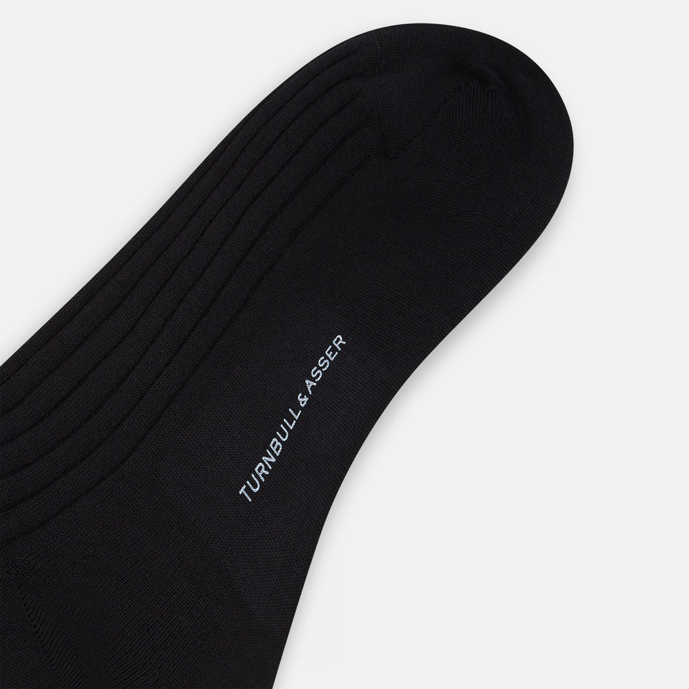 The Turnbull & Asser Black Wool Long Sock stands upright on a white background, featuring a ribbed texture with a fitted foot and calf, ideal for those seeking stylish over the calf socks.