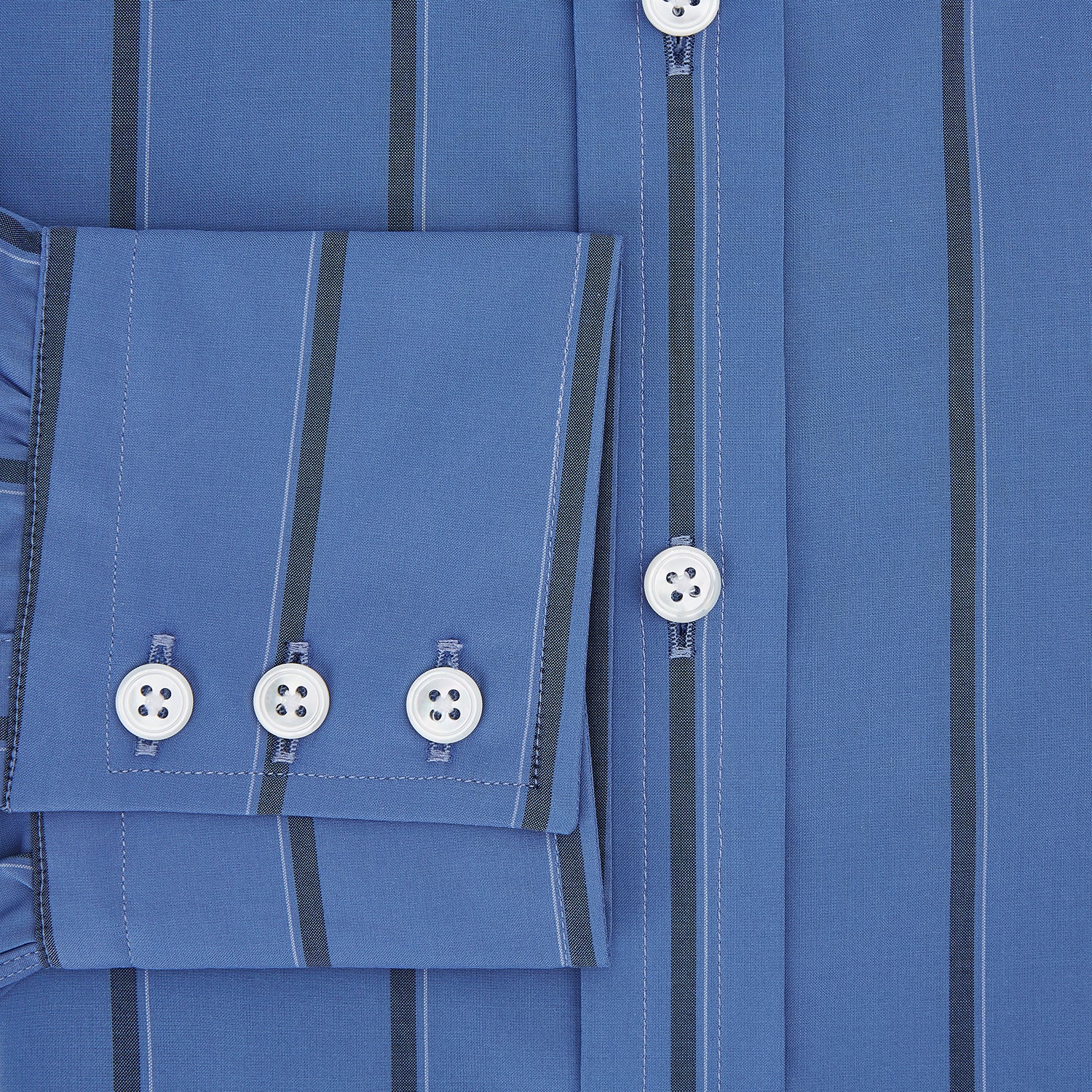 View 4 of product The Turnbull & Asser Colony Blue Track Stripe Mayfair Shirt is crafted from Italian cotton with long sleeves, dark blue track stripes, a classic collar, and buttoned cuffs, shown against a white background.
