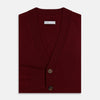 View 4 of product The Turnbull & Asser Burgundy Cashmere Cardigan features a V-neck, ribbed cuffs and hem, two front pockets, and a classic button-up design, shown on a plain white background.