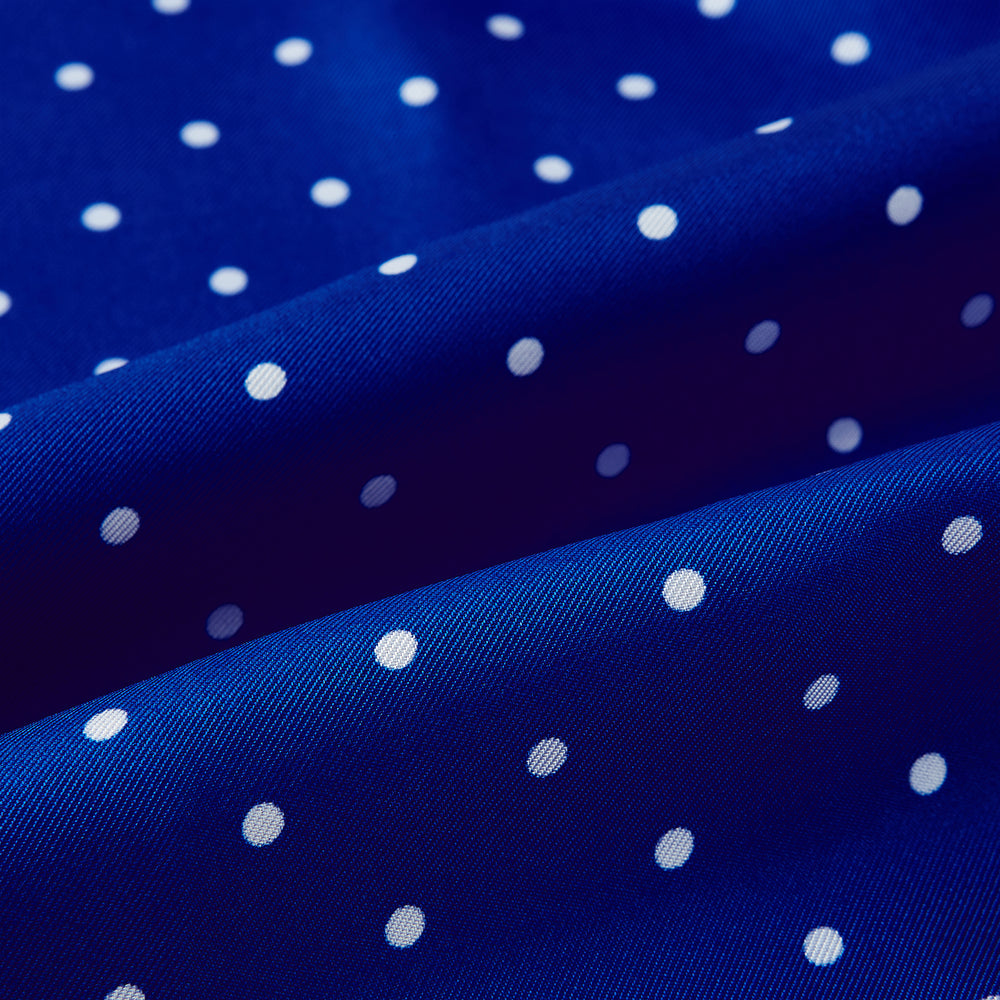 The Turnbull & Asser Royal Blue and White Spotted Silk Scarf features evenly spaced small white dots, fringed edges, and the brand’s name printed near the ends.