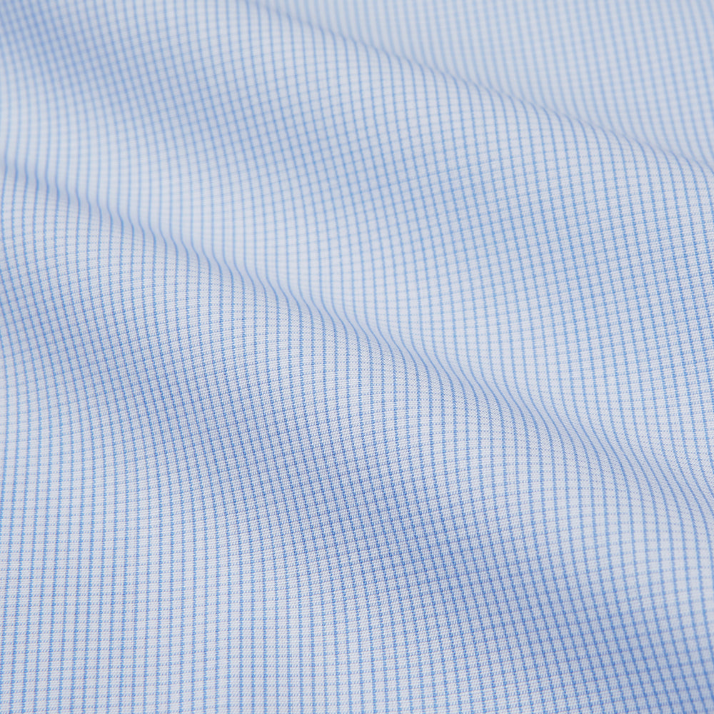 The Turnbull & Asser Micro Blue Check with White Collar and Cuff Shirt, a light blue long-sleeve style, features contrasting white collar and cuffs, buttoned down the front and laid flat on a white background.