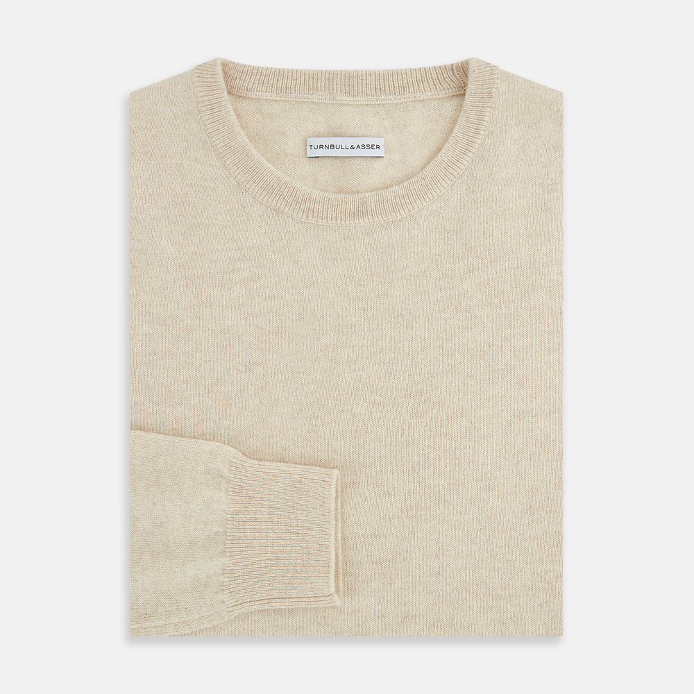 The Turnbull & Asser Cream Cashmere Round Neck Jumper features long sleeves, ribbed cuffs, and a ribbed hem—a versatile men’s knitwear staple, shown against a white background.