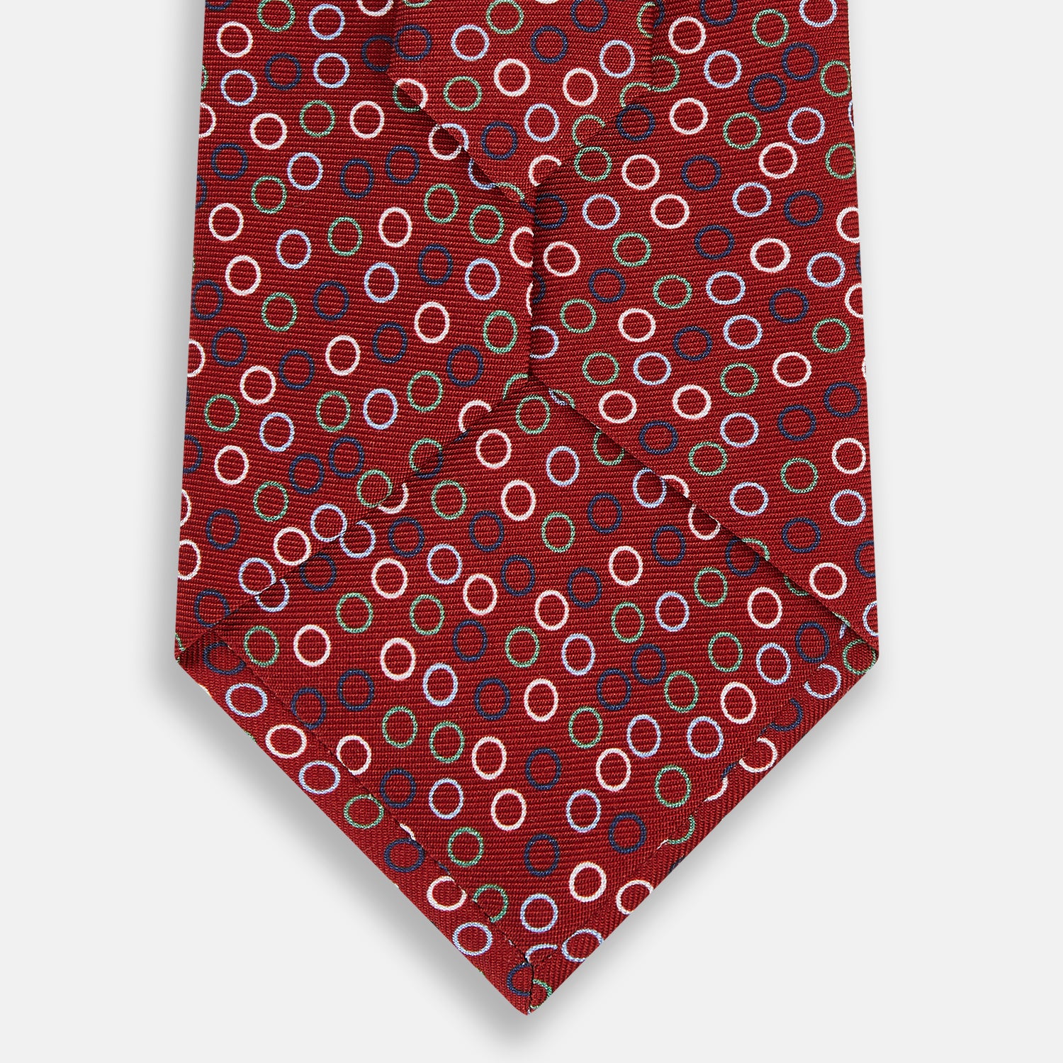 View 3 of product The Turnbull & Asser Pink and Navy Circle Red Silk Tie features small multicolored rings on red fine English silk. Rolled and displayed on a plain white background, this elegant accessory combines classic style with vibrant accents.