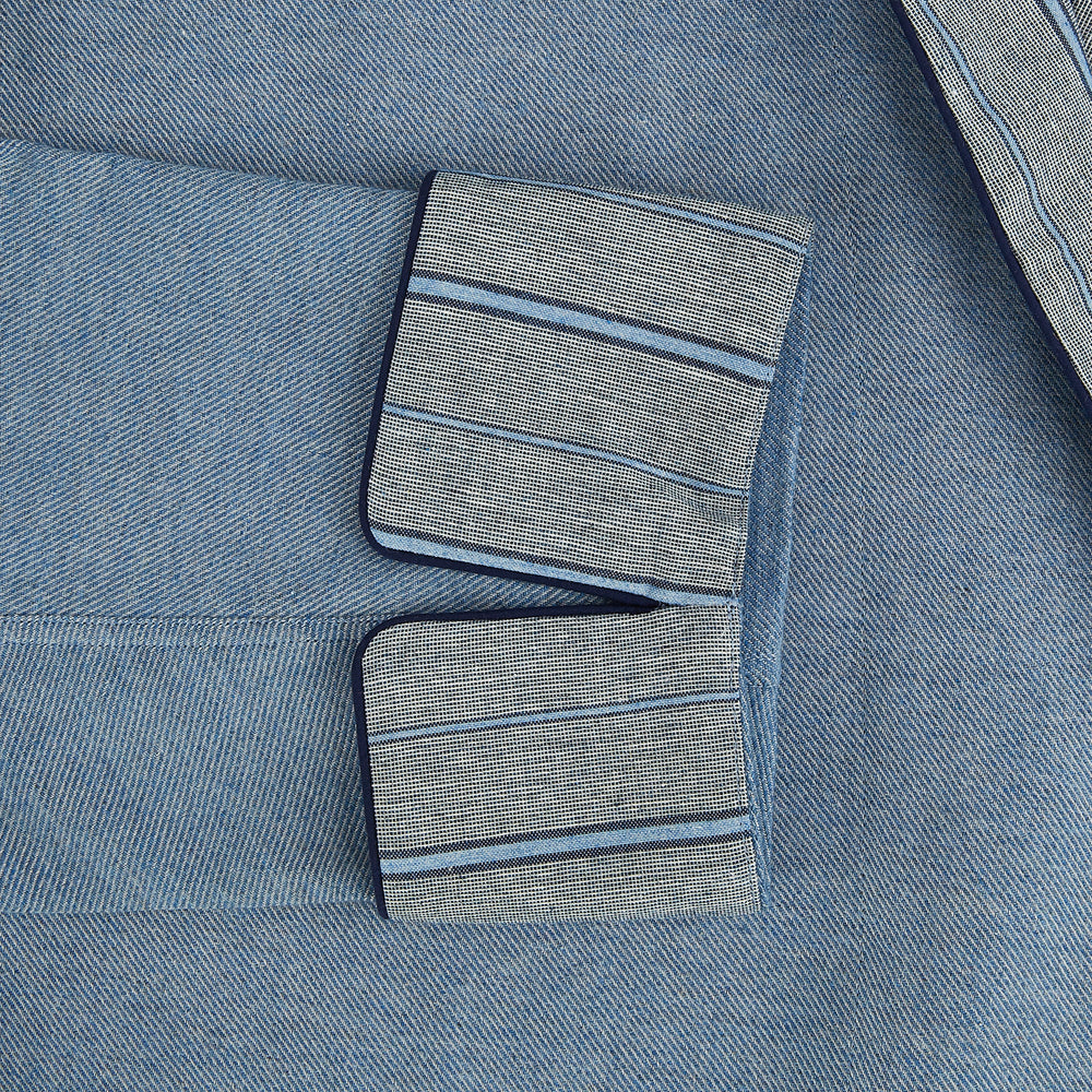 The Turnbull & Asser Blue Stripe Collar Cotton Twill Gown features a light blue hue, striped collar and cuffs, long sleeves, patch pockets, and a matching belt for elevated home comfort. Shown on a white background.