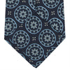 View 3 of product The Jacquard Silk Geometric Tie by Turnbull & Asser features a navy blue base with light blue and white star and circle motifs, shown rolled on a white background.
