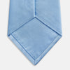 View 4 of product The Turnbull & Asser SATIN RIVER TIE, a neatly rolled light blue silk accessory with a smooth matte finish, is displayed against a plain white background.
