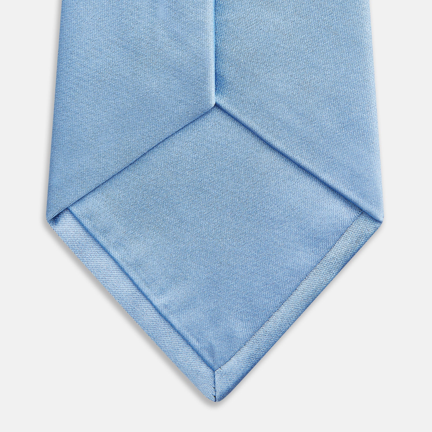 View 4 of product The Turnbull & Asser SATIN RIVER TIE, a neatly rolled light blue silk accessory with a smooth matte finish, is displayed against a plain white background.
