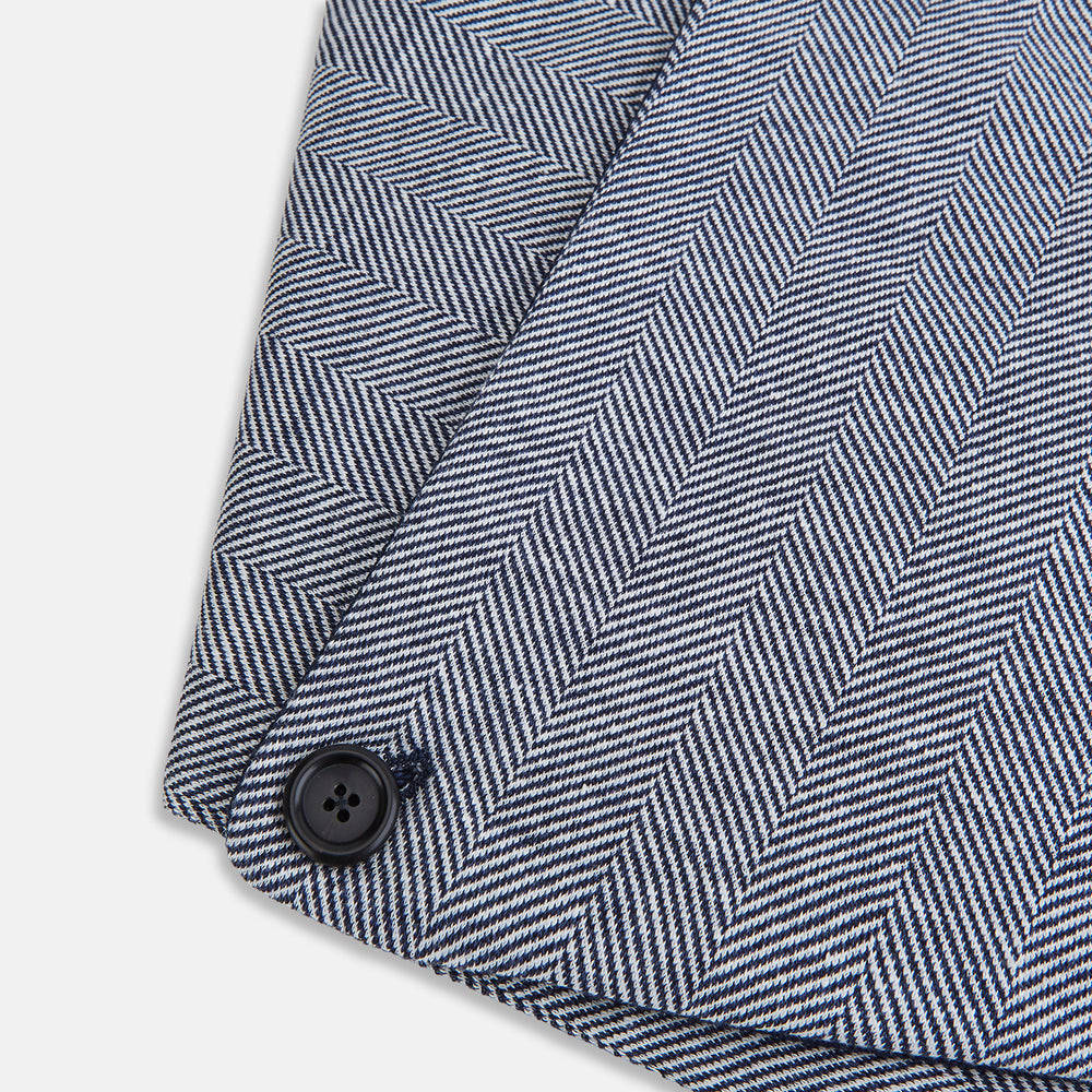 The Turnbull & Asser Navy Herringbone Silk and Linen Neck Warmer features a grey and white pattern, button closure, and dark navy lining—a refined formal accessory for any wardrobe.