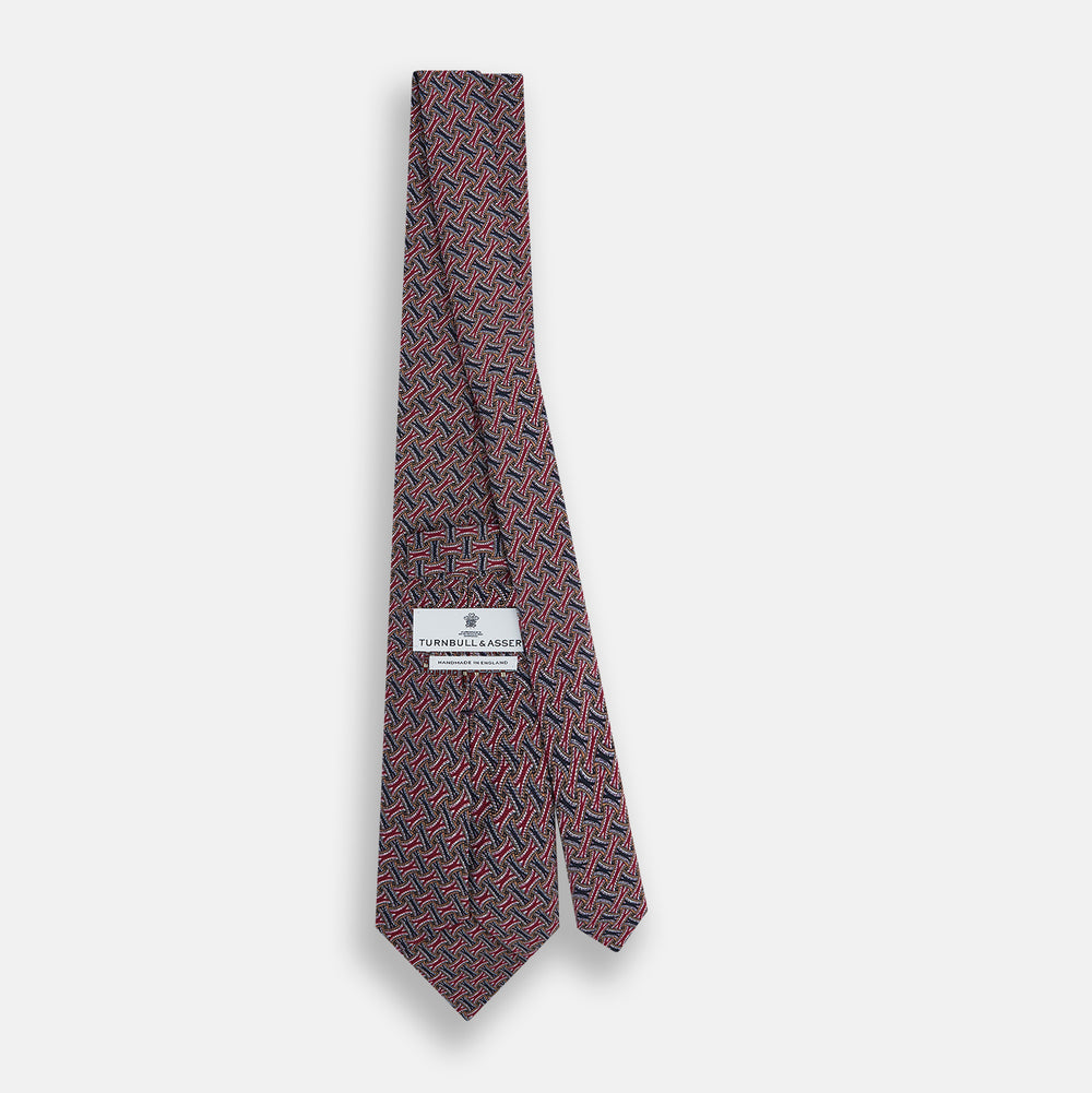 The Turnbull & Asser Burgundy and Navy Weave Patterned Silk Tie features a geometric design in rich tones on silk fabric.