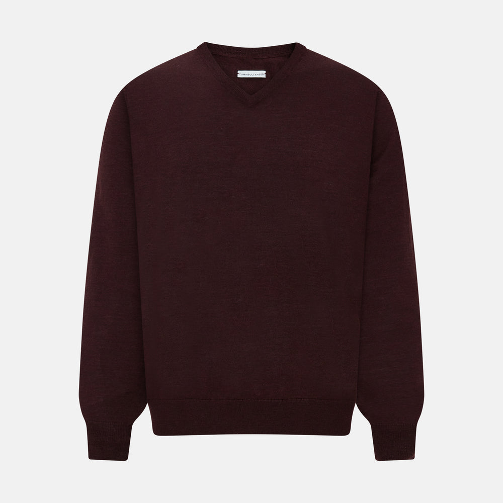 The Turnbull & Asser Burgundy Fine Merino V-Neck Jumper features a classic plain knit design with long sleeves, showcased against a crisp white background.