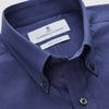 View 3 of product The Blue Piece Dyed Weekend Fit Suffolk Shirt by Turnbull & Asser features a button-down Dorset collar, chest pocket, white buttons, and long sleeves in classic navy, laid flat against a white background.