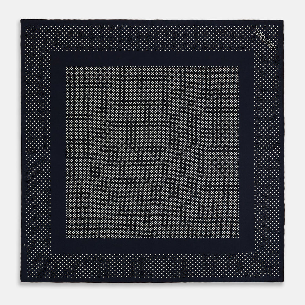 The Turnbull & Asser Navy and Cream Dot Silk Pocket Square features small cream dots, a border design, and displays handmade craftsmanship with one corner folded to show the reverse side.