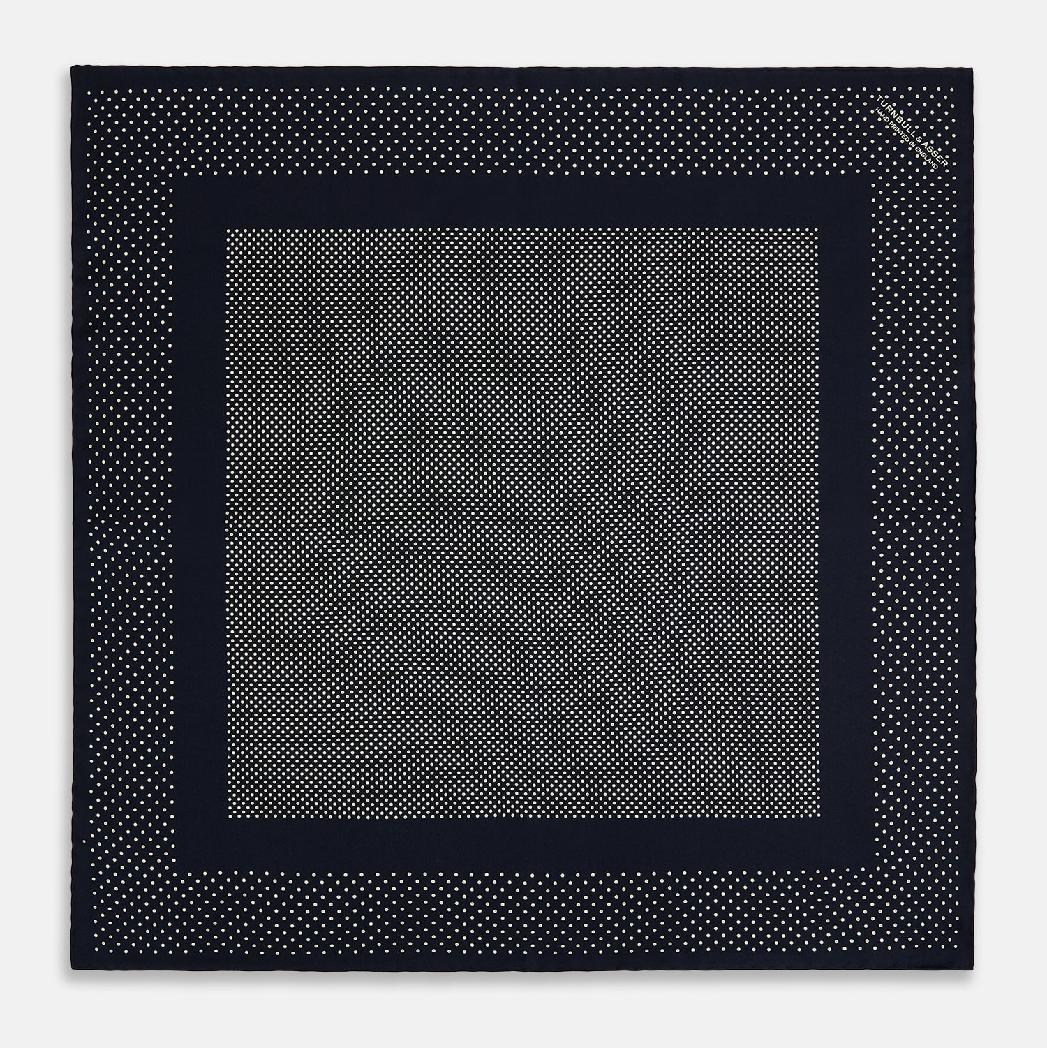 View 4 of product The Turnbull & Asser Navy and Cream Dot Silk Pocket Square features small cream dots, a border design, and displays handmade craftsmanship with one corner folded to show the reverse side.