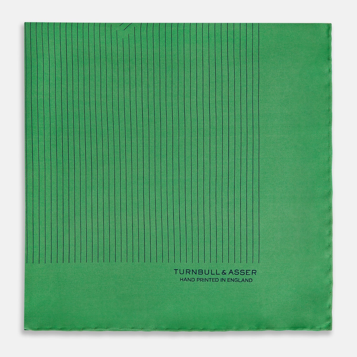 View 4 of product The Hunter Green Stripe Silk Pocket Square by Turnbull & Asser features thin black vertical stripes on one corner and “Turnbull & Asser Hand Printed in England” printed in black, reflecting classic British heritage.