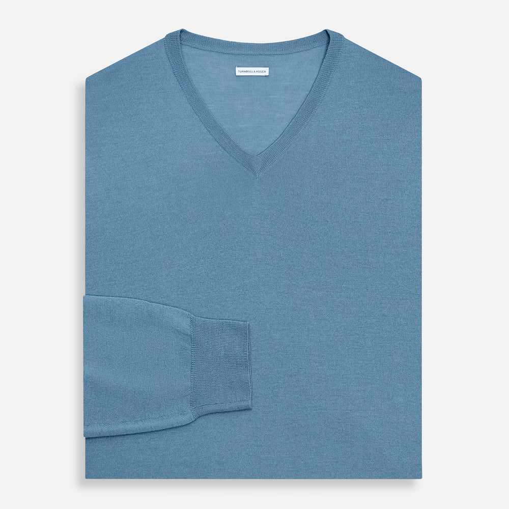 The Turnbull & Asser Pale Blue Fine Merino V-Neck Jumper features long sleeves, ribbed cuffs, and a straight hem. Shown against a white background, this classic knitwear combines comfort and style.
