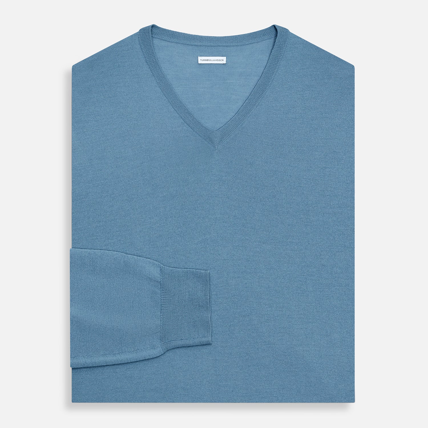 View 4 of product The Turnbull & Asser Pale Blue Fine Merino V-Neck Jumper features long sleeves, ribbed cuffs, and a straight hem. Shown against a white background, this classic knitwear combines comfort and style.