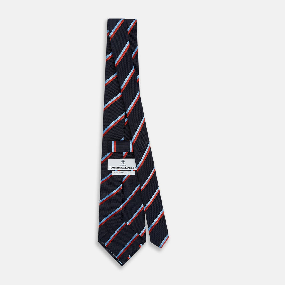 The Turnbull & Asser Red And Blue Stripe Silk Blend Tie, rolled on a white background, features refined diagonal accents—an elegant formal accessory.
