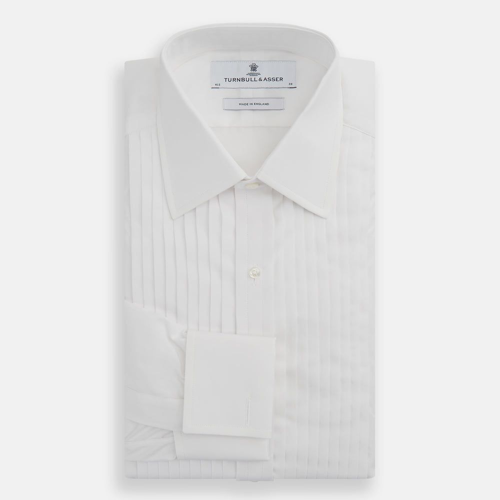 The Turnbull & Asser White Pleated Cotton Dress Shirt features a T&A collar, double cuffs, a button-down front, elegant chest pleats, and a slightly curved hem for a classic formal look.