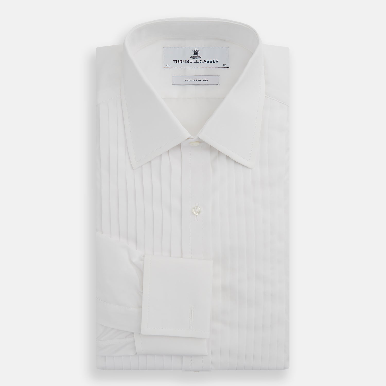 View 5 of product The Turnbull & Asser White Pleated Cotton Dress Shirt features a T&A collar, pleated front, double cuffs, and a button-down front, shown laid flat against a white background.
