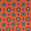 View 3 of product The Great Gatsby Orange Printed Silk Tie by Turnbull & Asser, from the Legends collection, features a repeating pattern of small blue, white, and yellow floral motifs—an ideal summer accessory—shown rolled on a white background.