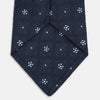 View 4 of product The Turnbull & Asser Jacquard Silk Circle Tie showcases a textured navy blue design with small white and light blue floral motifs—an essential accessory for refined attire.