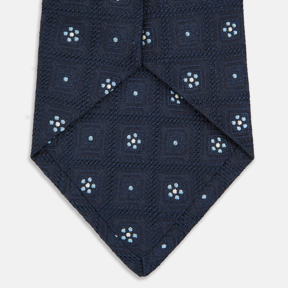The Turnbull & Asser Jacquard Silk Circle Tie showcases a textured navy blue design with small white and light blue floral motifs—an essential accessory for refined attire.