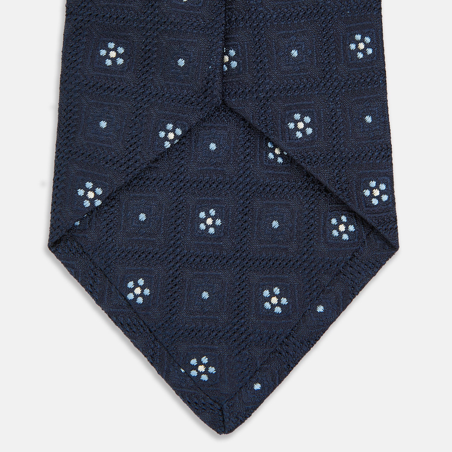 View 4 of product The Turnbull & Asser Jacquard Silk Circle Tie showcases a textured navy blue design with small white and light blue floral motifs—an essential accessory for refined attire.