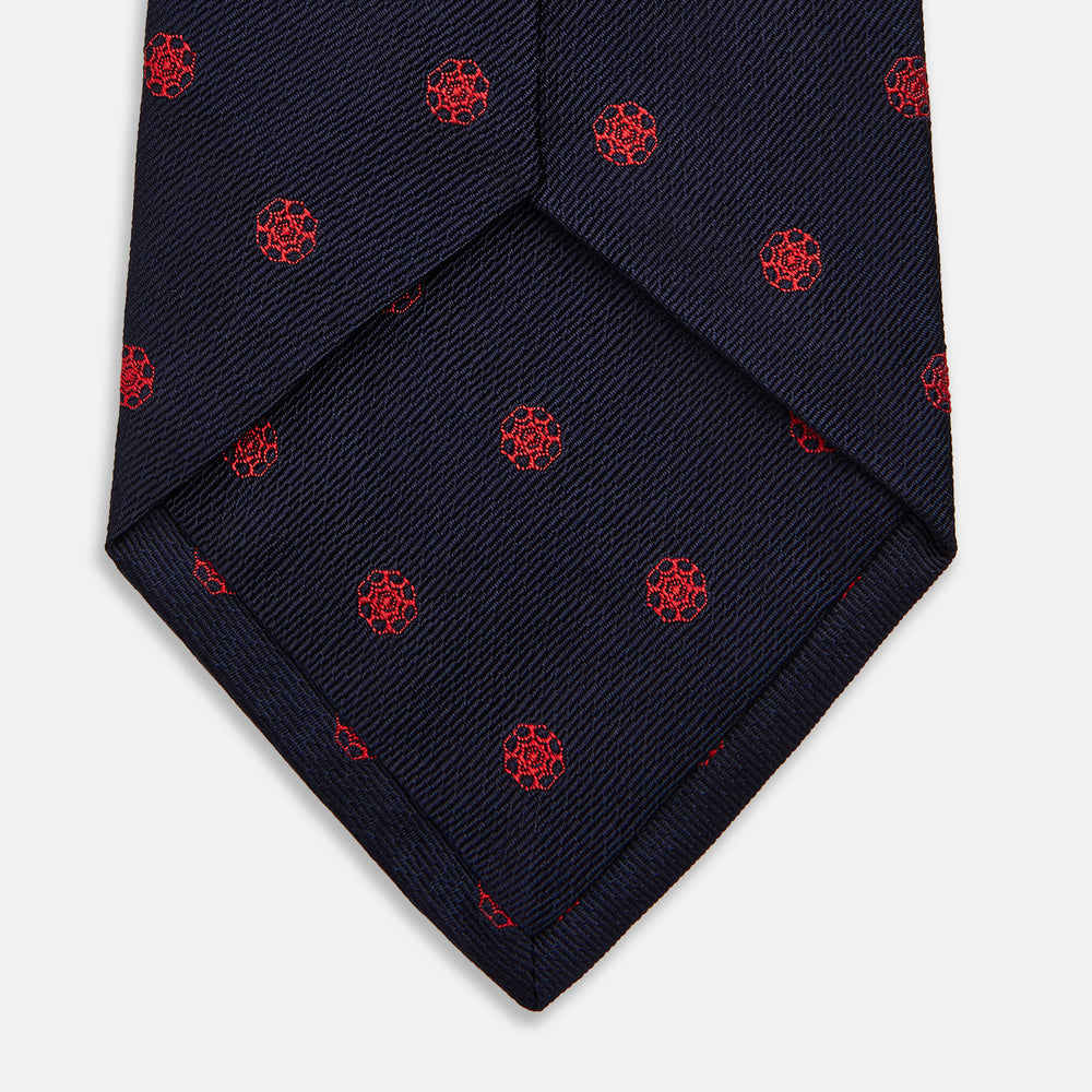 The EMBLEM SPOT NAVY TULIP TIE by Turnbull & Asser features a navy base with red circle motifs, neatly rolled on a white background—an essential accessory for refined style.
