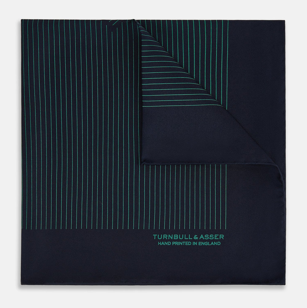 The Turnbull & Asser Navy and Hunter Green Stripe Silk Pocket Square features thin green stripes, hand-rolled edges, and "TURNBULL & ASSER HAND PRINTED IN ENGLAND" in green on the bottom right corner.
