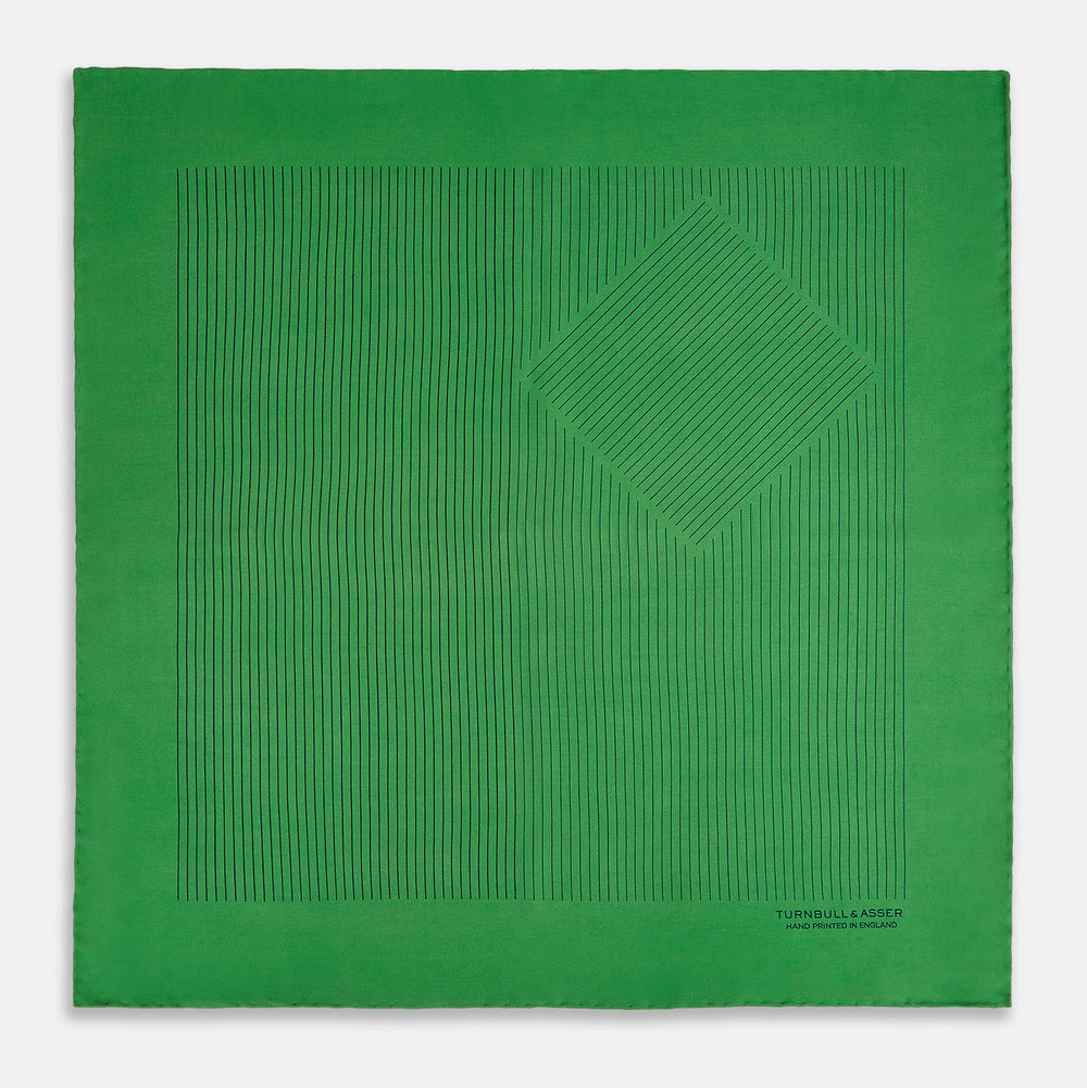 The Hunter Green Stripe Silk Pocket Square by Turnbull & Asser features thin black vertical stripes on one corner and “Turnbull & Asser Hand Printed in England” printed in black, reflecting classic British heritage.